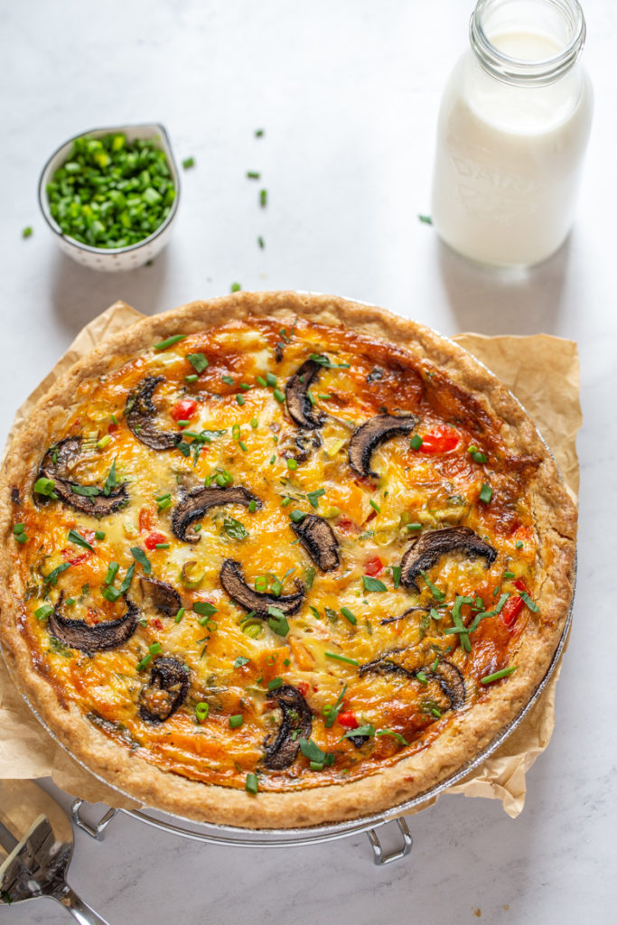 Whole vegetable quiche with bottle of milk and fresh chives