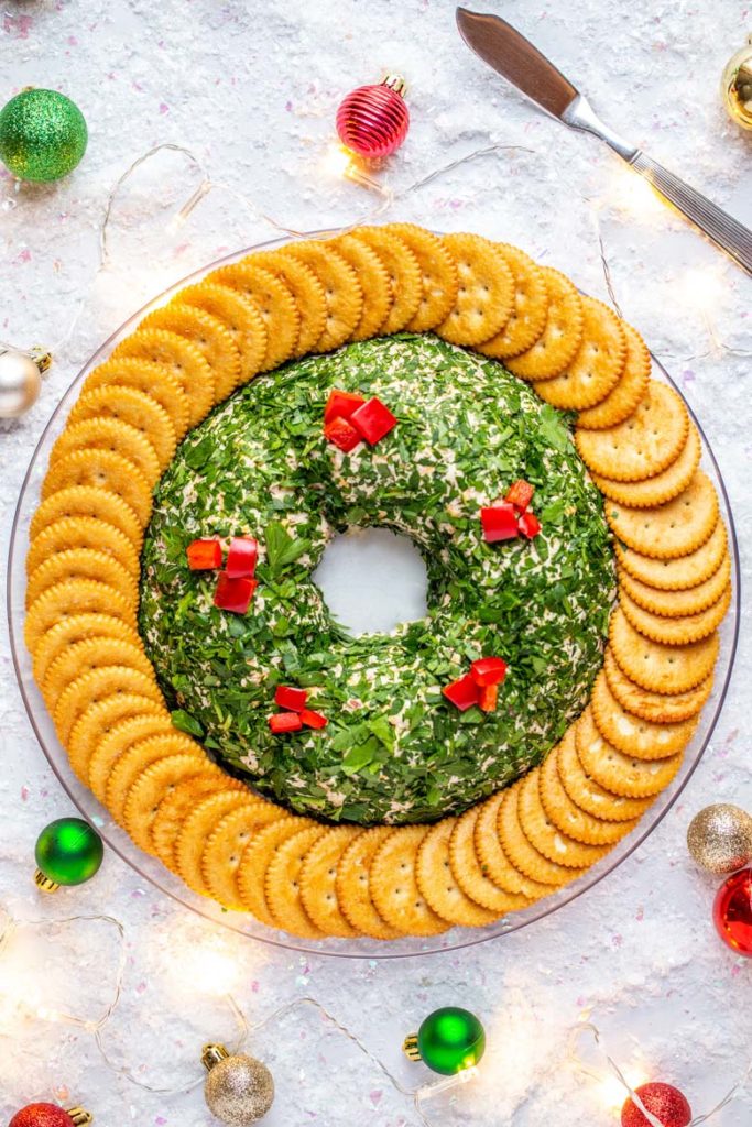 Bacon Cheese Ball Wreath on a platter surrounded by tiny ornaments and string lights for a festive presentation
