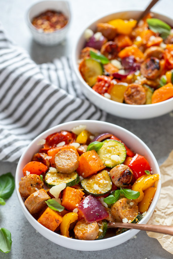 Close up bowl of Sheet pan chicken sausages and veggies.