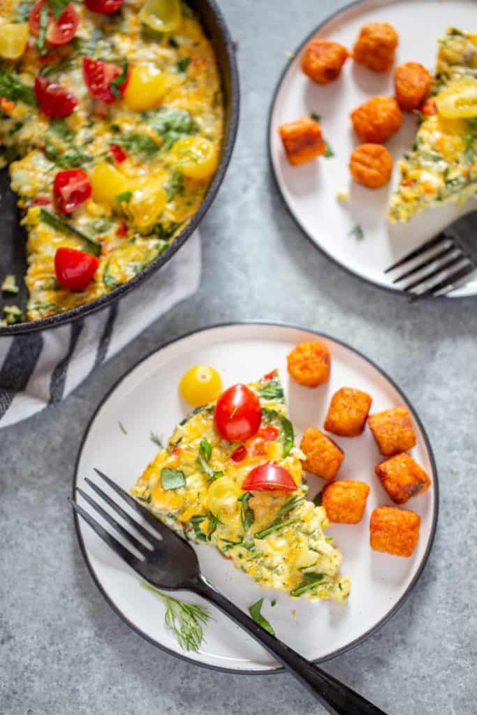 A slice of Garden Herb Frittata on a plate with sweet potato tots