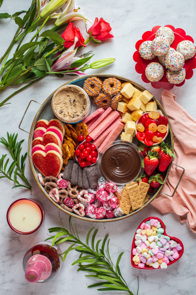 Round tray of cookies, candy, chocolate, edible cookie dough, tea cakes and strawberries for Valentine's day dessert board