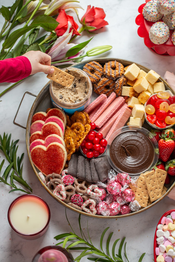 Round tray of cookies, candy, chocolate, edible cookie dough, tea cakes and strawberries for Valentine's day dessert board