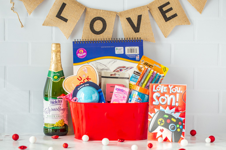 Valentine's day gift basket for son, boy, filled with a drawing pad, pencils, erasers, bath bomb, slime and some sparkling white grape juice.
