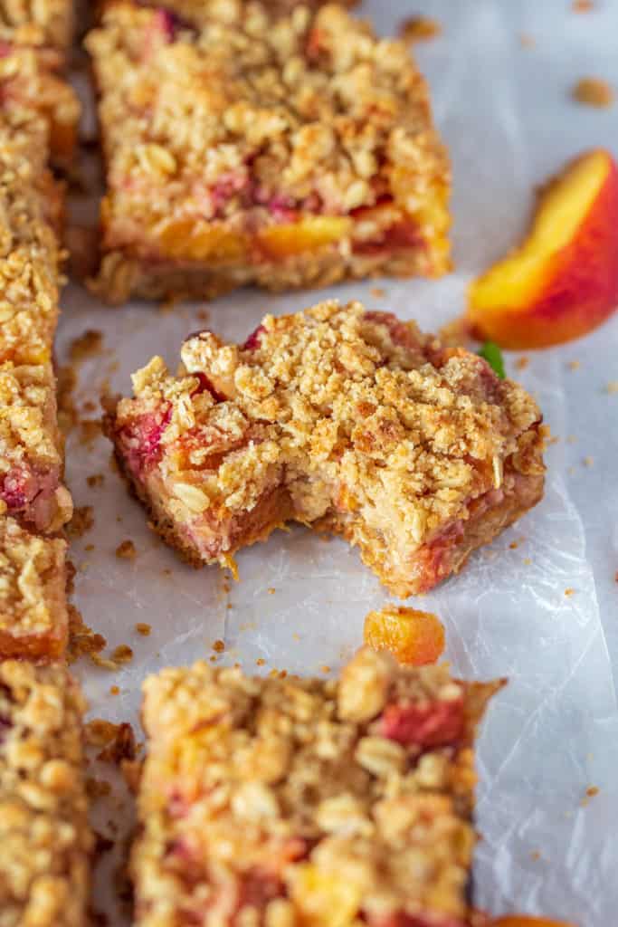 Close up shot of piece of peach cobbler crumble bars with bite taken out.
